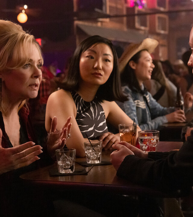 "Hacks - Mädelsabend, jung und alt": In einer belebten Bar: Deborah (Jean Smart) spricht ernst gestikulierend zu Ava (Hannah Einbinder), während Kiki (Poppy Liu) mit neutralem Gesichtsausdruck zu Ava schaut.