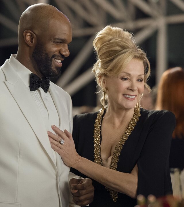 "Hacks - Verändere die Welt mit Lachern": Deborah (Jean Smart) steht im schicken Abendkleid neben dem mit weißen Smoking festlich gekleidetem Marcus (Carl Clemons-Hopkins). Deborah hat ihre Hand auf dessen Brust gelegt und beide lachen glücklich und gelöst. Im Hintergrund befinden sich weitere Personen (Komparsen).