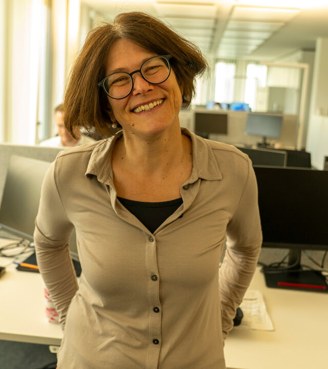 "einfach Mensch - Grit Böhnisch: Cochlea-Implantat- Ja oder Nein?": Grit Böhnisch steht im Büro vor ihrem Schreibtisch und schaut lächelnd in die Kamera.