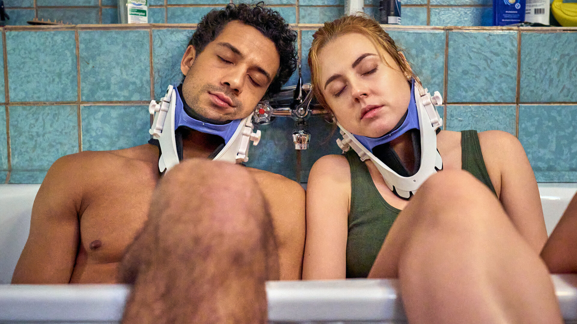 "Ich dich auch! - Das Herz": Yannik (Rojan Juan Barani) und Caro (Meriel Hinsching) sitzen mit geschlossenen Augen in der Badewanne. Beide tragen eine Halskrause. Sie lehnen sich an der Wand an. Ihre Beine hängen aus der Wanne heraus.