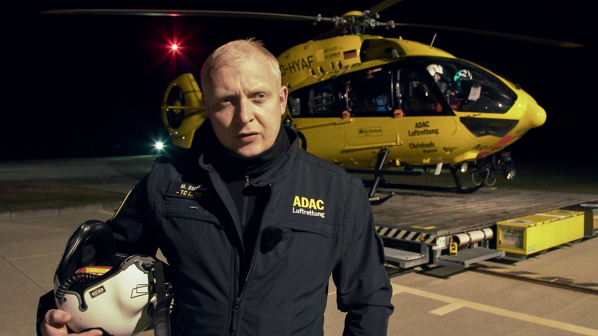 "37° Guten Morgen Feierabend! - Leben mit der Nachtschicht": Der Notfallsanitäter Martin steht vor dem gelben ADAC-Hubschrauber, er hält seinen Helm im Arm.