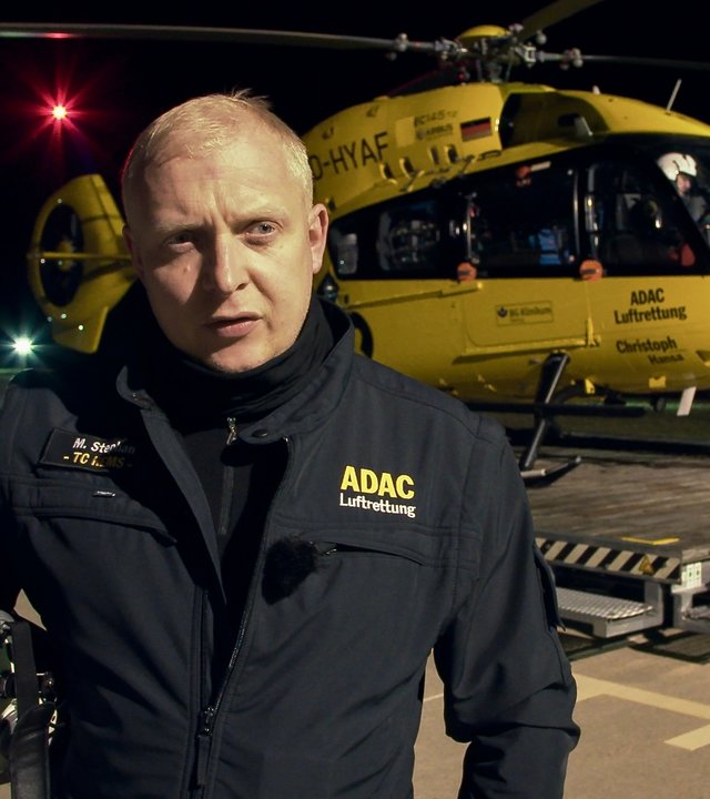 "37° Guten Morgen Feierabend! - Leben mit der Nachtschicht": Der Notfallsanitäter Martin steht vor dem gelben ADAC-Hubschrauber, er hält seinen Helm im Arm.