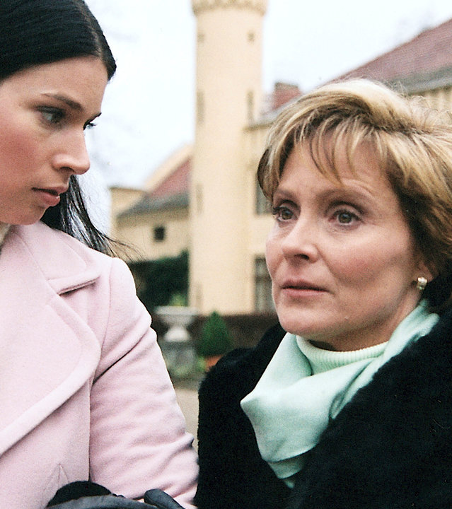 "Bianca - Wege zum Glück: Kapitel 98": Spaziergang vor dem Gutshof: Judith (Elisabeth Sutterlüty) dreht sich hin zu Ariane. Ariane (Kerstin Gähte) hat sich bei Judith im Arm eingehängt und schaut gedankenverloren vor sich hin.