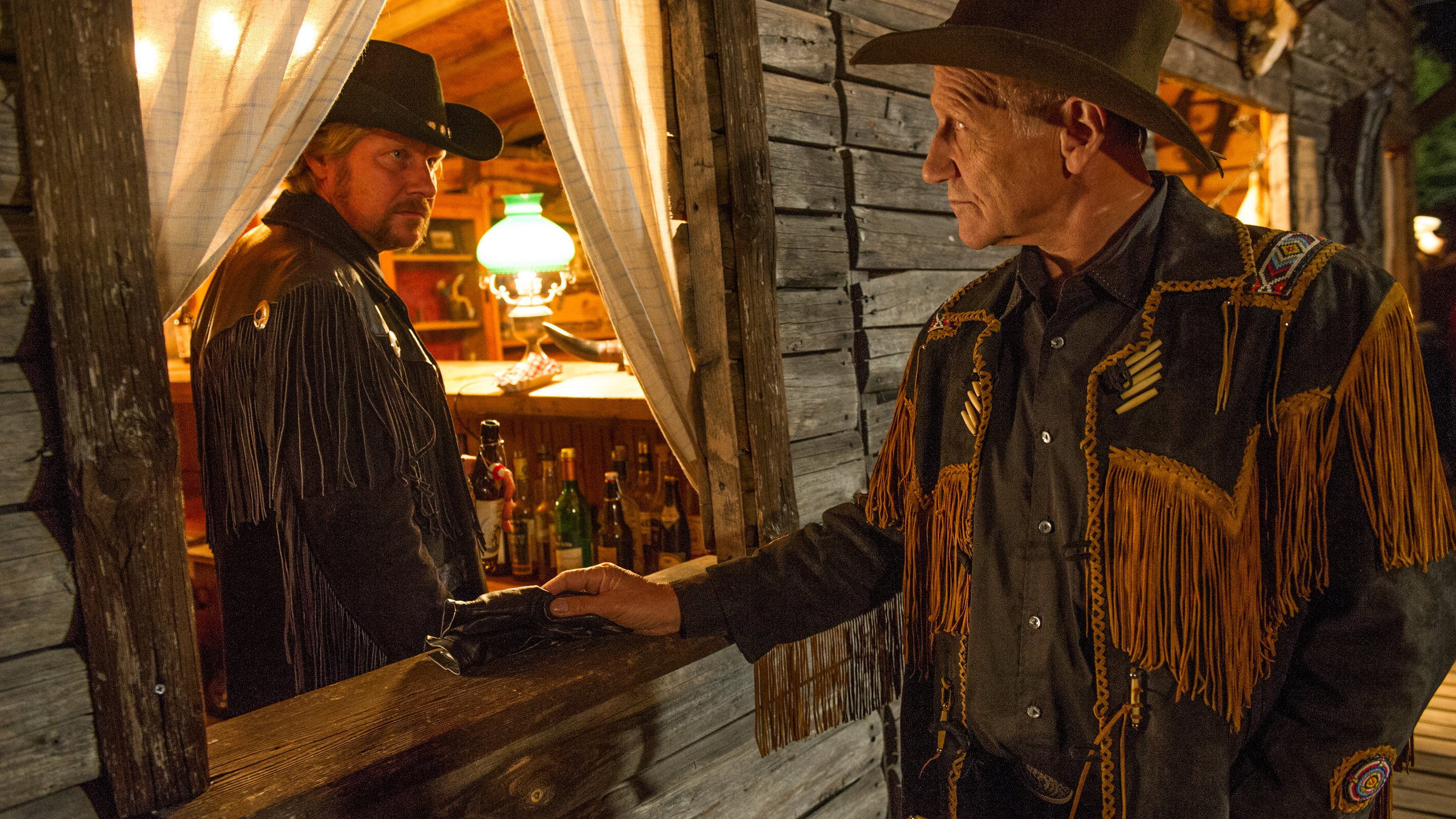 "SOKO Stuttgart - Gelobtes Land": Im Saloon steht Andy Hartmann (Martin Luding) hinter der Theke. Durch ein Fenster unterhält sich Michael Kaiser (Karl Kranzkowski) von außen mit ihm. Kaiser fallen Andys schwarze Lederhandschuhe auf.