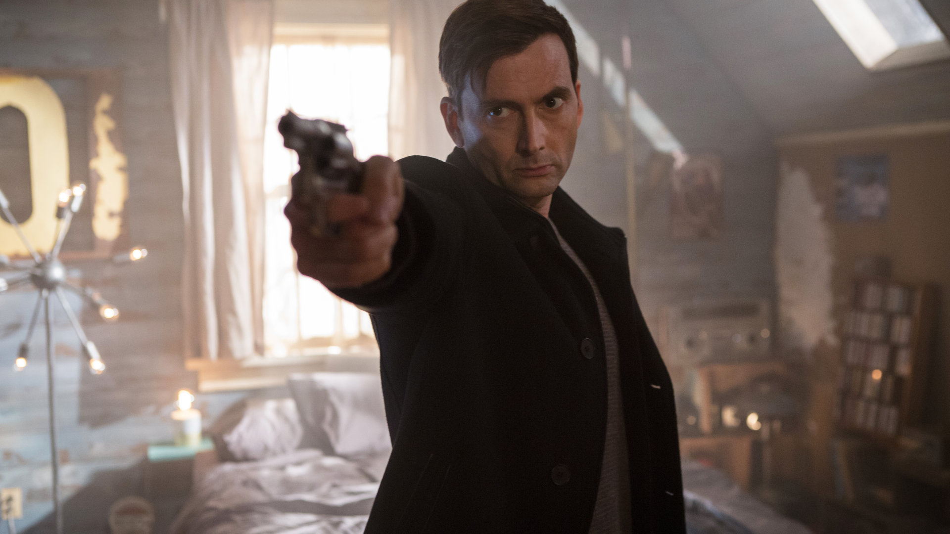 "Im Visier des Killers": Cale Erendreich (David Tennant) steht mit gezogener Waffe in einem Schlafzimmer.