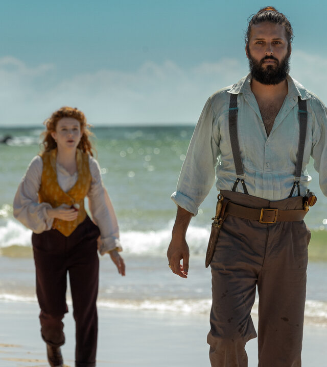 "Nautilus - Die unbekannte Insel": Nemo (Shazad Latif), Humility (Georgia Flood) und Blaster (Kayden Price) laufen hintereinander über einen Strand. Im Hintergrund liegt das Meer.