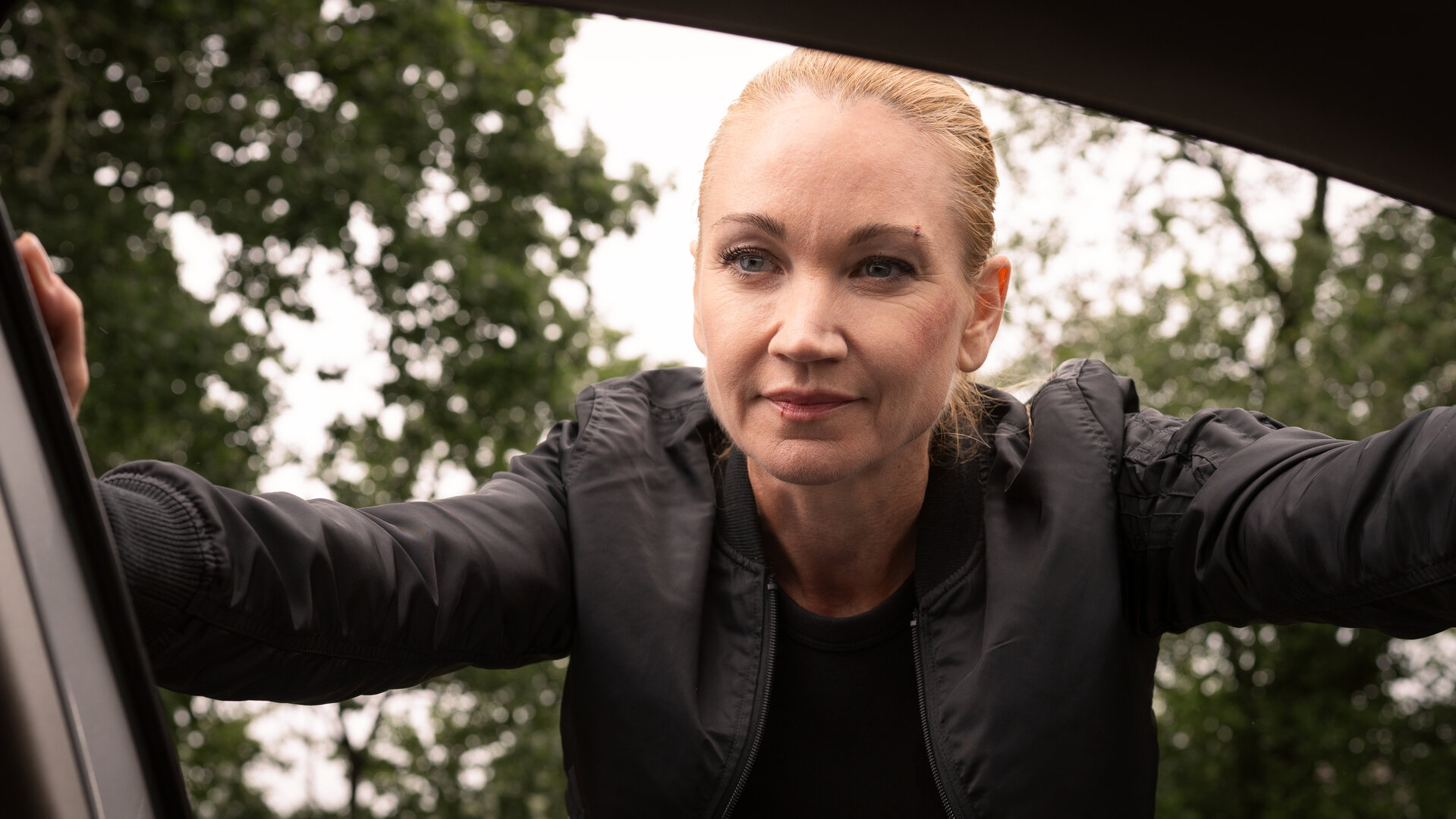 "Sarah Kohr – Bis auf den Grund": Sarah Kohr (Lisa Maria Potthoff) schaut selbstsicher lächelnd durch das Fenster in das Innere eines Wagens.