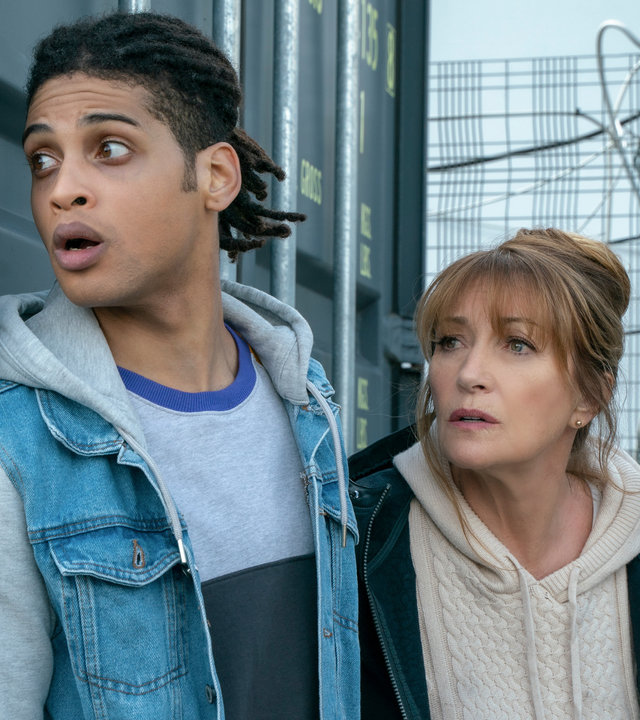 "Harry Wild - Mörderjagd in Dublin: Operation Mincemeat": Harry Wild (Jane Seymour) und Fergus Reid (Rohan Nedd) verstecken sich hinter einem grauen Container.