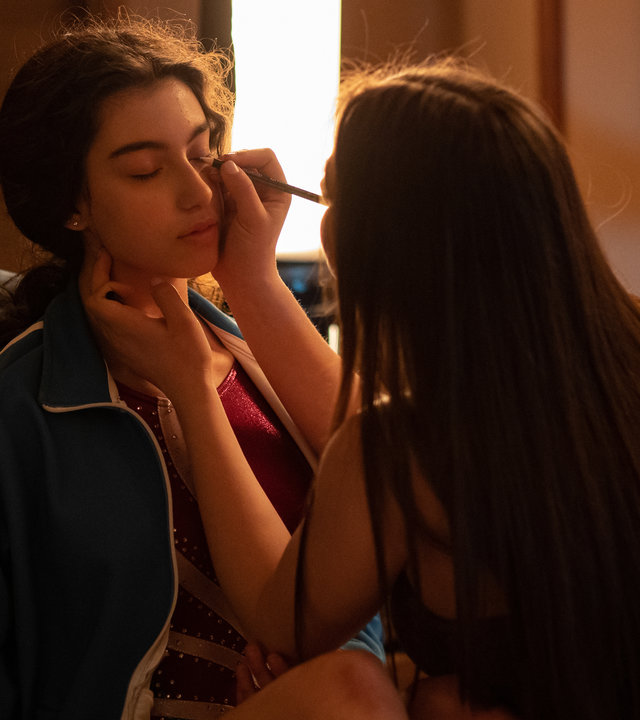 "The Gymnasts: Mittwoch": Martina (Alessia De Falco) wird von Carla (Giada Savi) für den Wettkampf geschminkt.