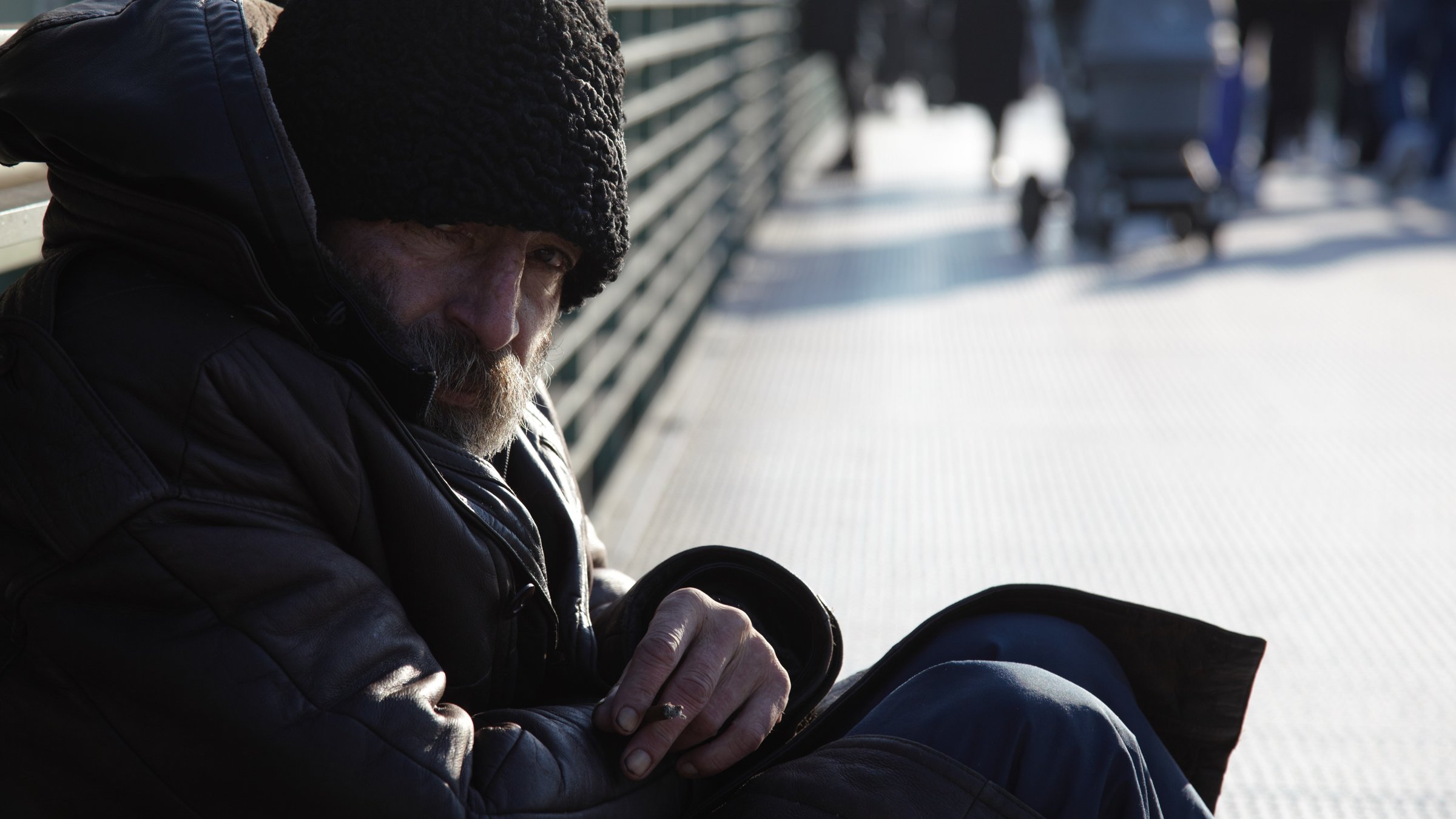 "ZDF.reportage: Berlin - Stadt der Bettler": Ein älterer Bettler mit Hut sitzt am linken Bildrand auf dem Boden einer Brücke.