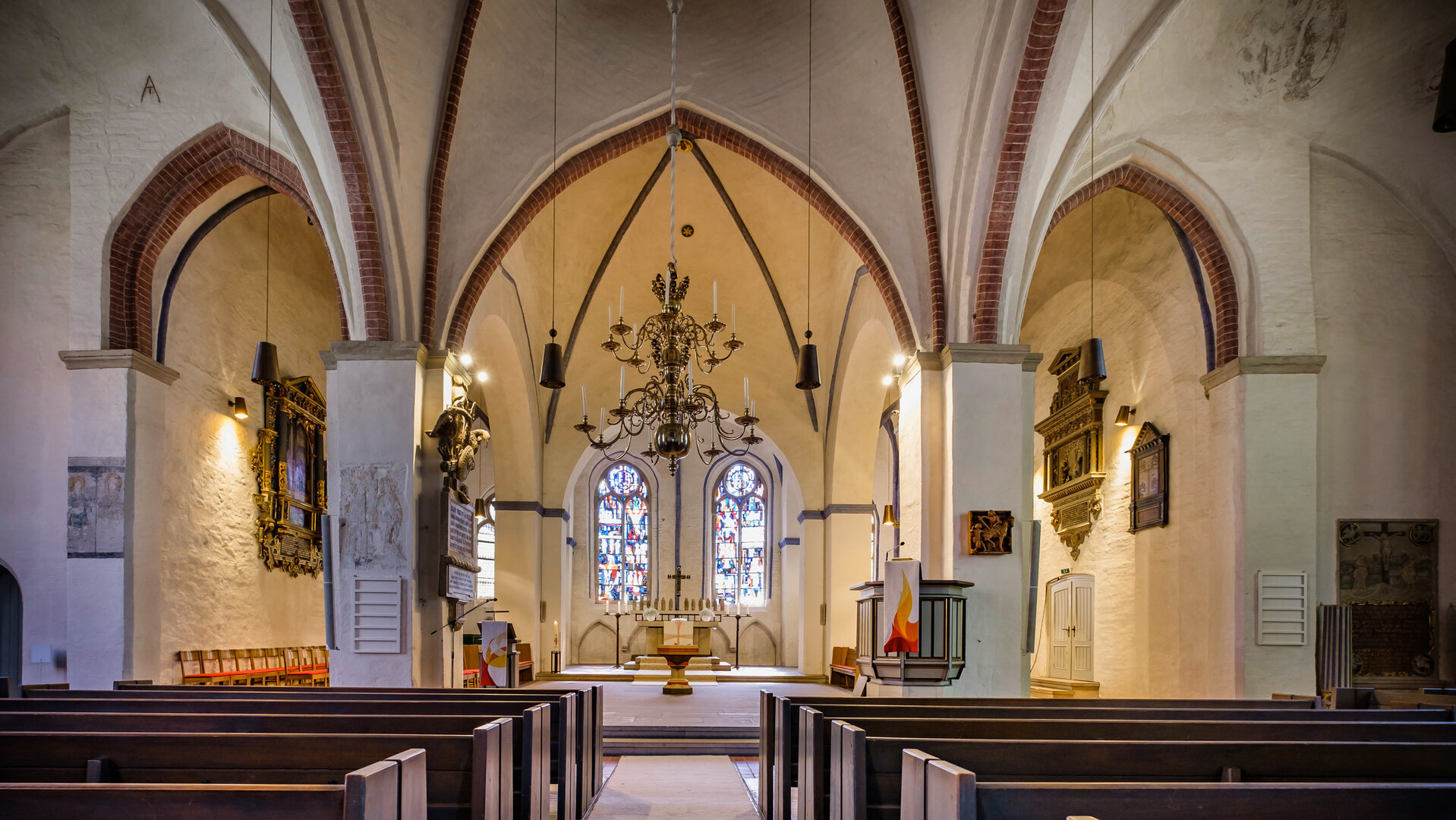 "Evangelischer Gottesdienst - Luft holen! Sieben Wochen ohne Panik": Im Innenraum der  Kirche St. Martin befinden sich spätgotische Bögen vor weißen, fast schmucklosen Wänden. Ein Kronleuchter aus dunklem Metall schwebt über dem Mittelgang. Im Hintergrund befindet sich der Altarraum mit bunten Glasfenstern.
