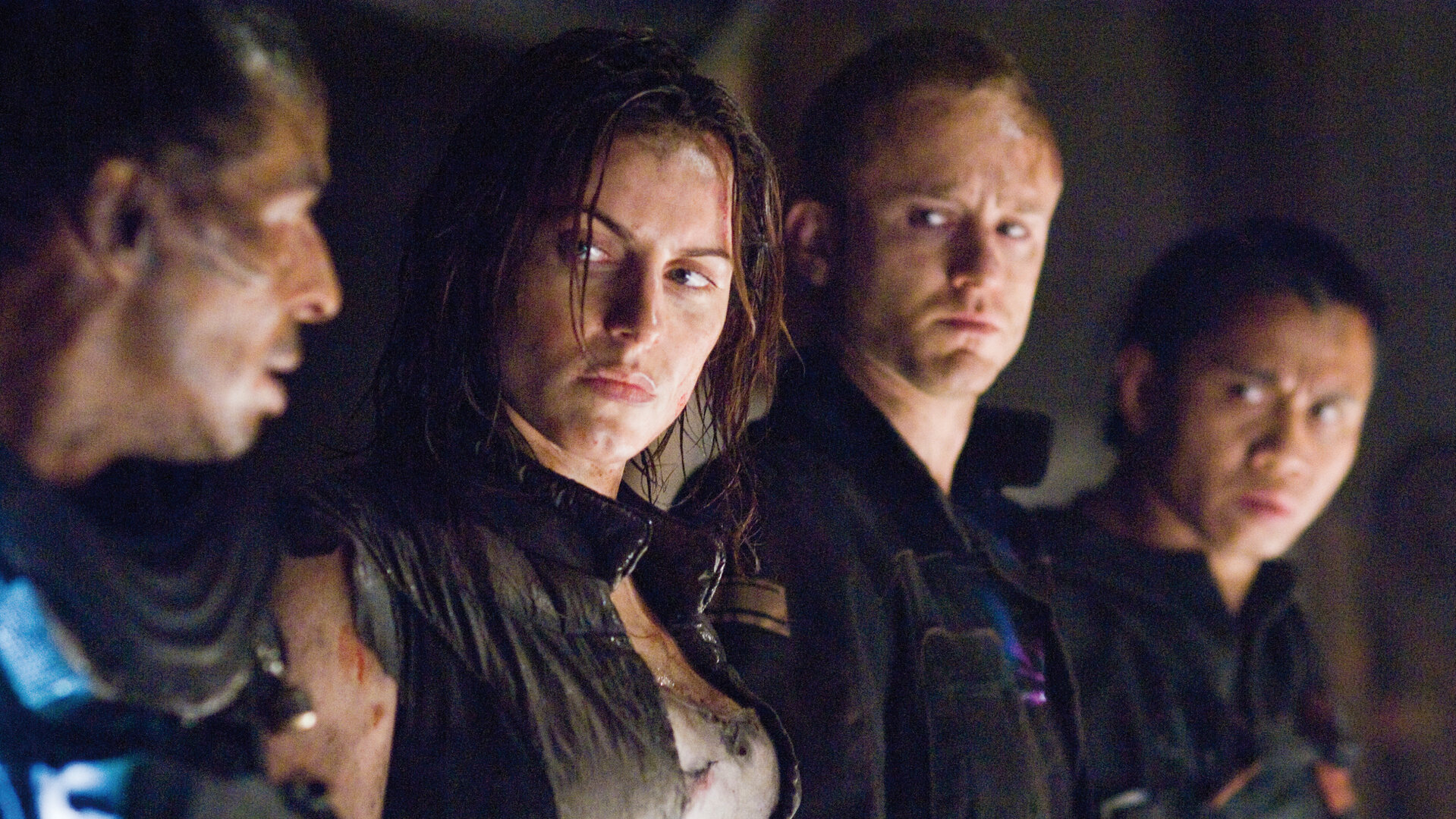 "Pandorum": Nadia (Antje Traue), Bower (Ben Foster) und Manh (Cung Le) stehen nebeneinander und blicken ernst zu Leland (Eddie Rouse), der ebenfalls neben ihnen steht.