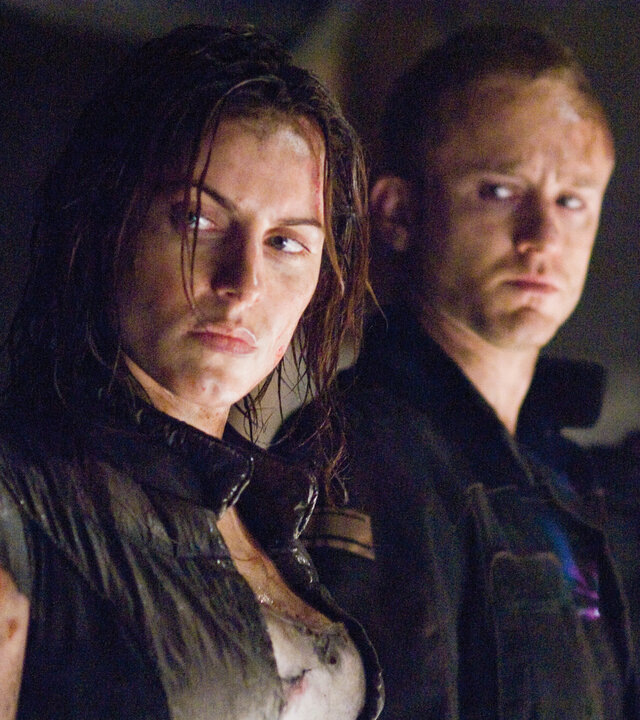"Pandorum": Nadia (Antje Traue), Bower (Ben Foster) und Manh (Cung Le) stehen nebeneinander und blicken ernst zu Leland (Eddie Rouse), der ebenfalls neben ihnen steht.
