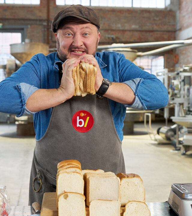 "besseresser: Die Tricks in Toastbrot & Co. - Sebastian Lege deckt auf": Sebastian Lege steht in seiner Werkstatt und drückt zwei Toastbrotscheiben gegeneinander.