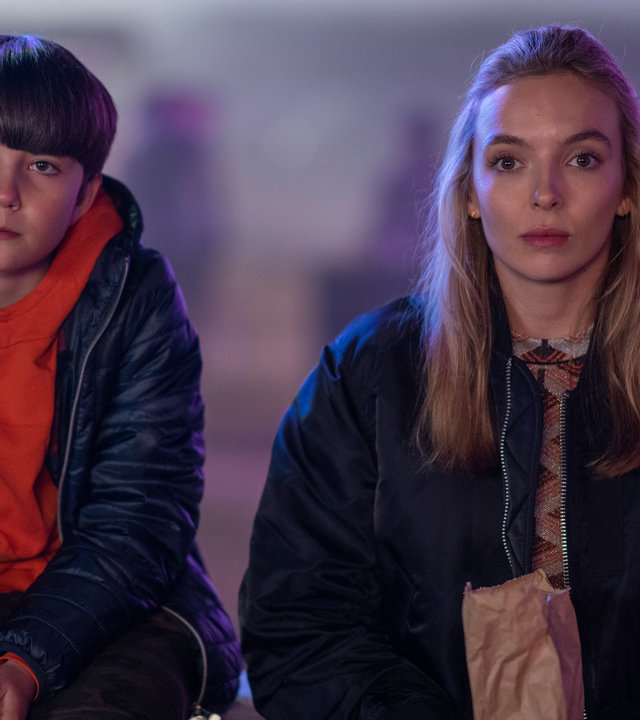 "Killing Eve - Mütterchen Russland": Villanelle (Jodie Comer) und Boris (Temirlan Blaev) sitzen gemeinsam auf einer Bank und schauen emotionslos nach vorne.