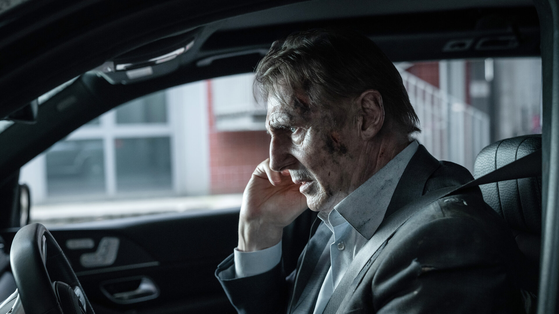 "Retribution - Vergeltung": Nahaufnahme: Matt (Liam Neeson) sitzt mit verschmutztem Gesicht und angespanntem Blick im Auto am Steuer.