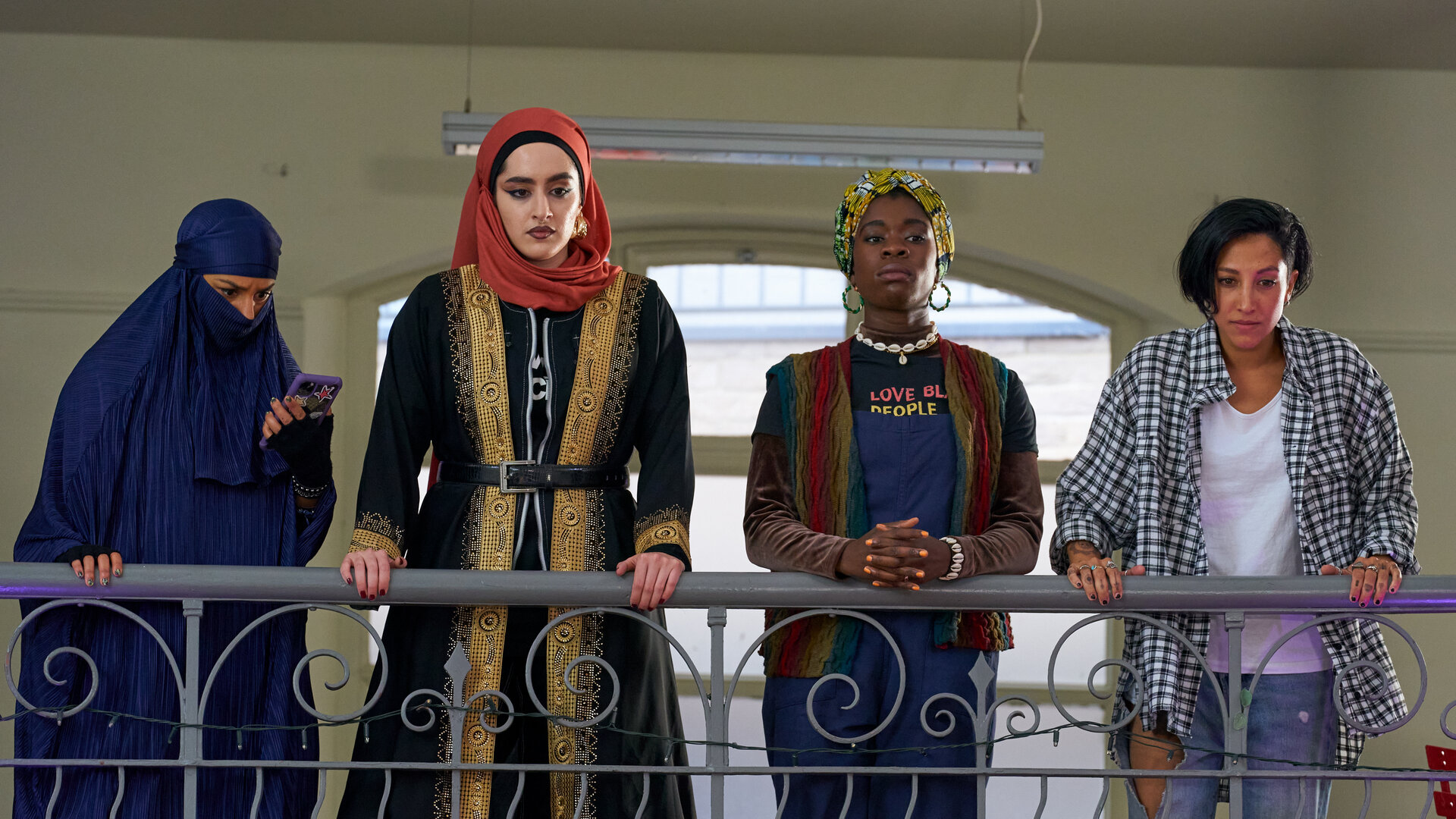 "We are Lady Parts - Spiel was vor": Momtaz (Lucie Shorthouse), Ayesha (Juliette Motamed), Bisma (Faith Omole) und Saira (Sarah Kameela Impey) stehen nebeneinander an einem Geländer und blicken konzentriert nach unten. Ihre Kleidung betont ihre Unterschiedlichkeit und bringt den individuellen Stil jeder Einzelnen zum Ausdruck.