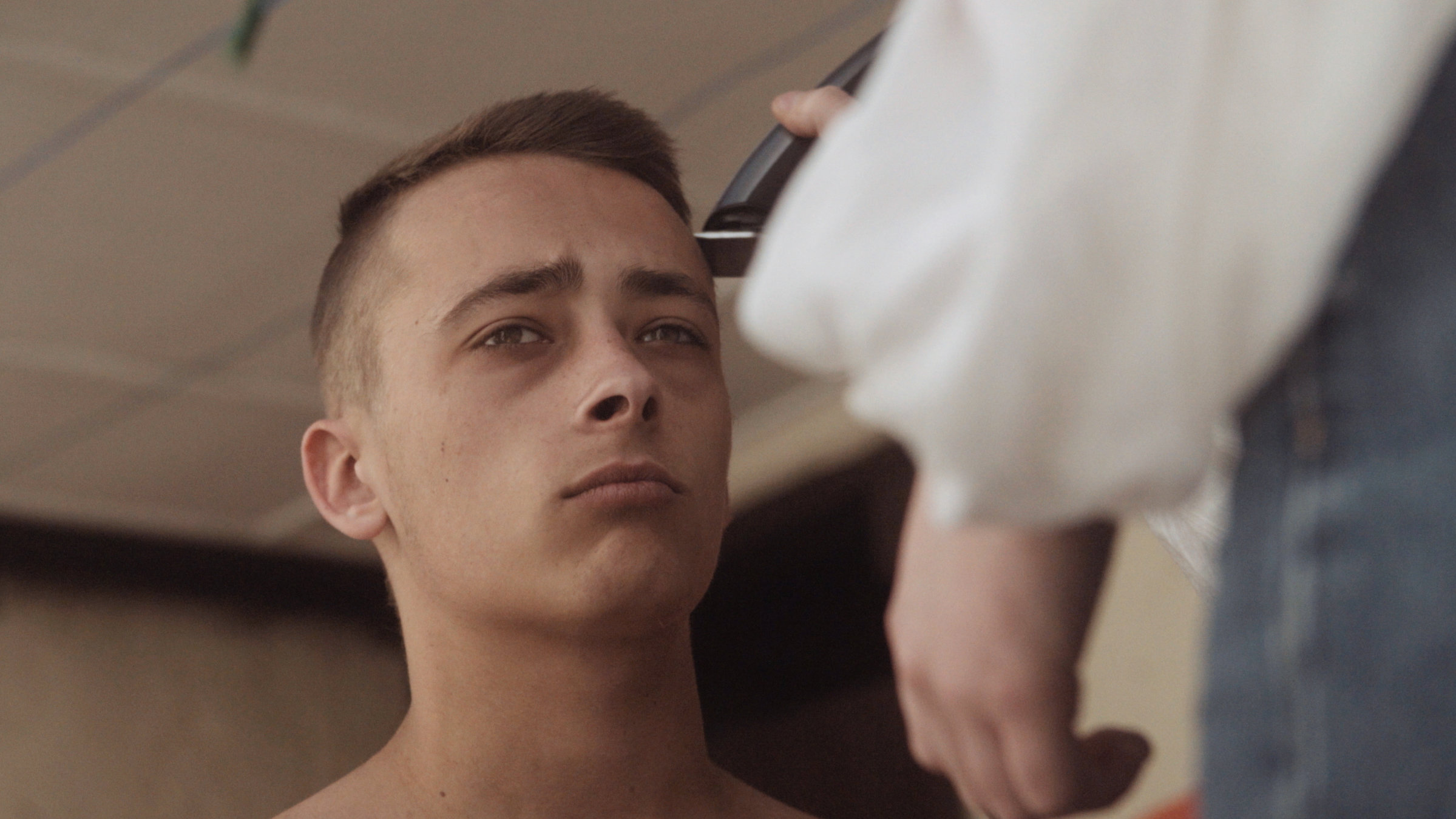 "Ab 18! - Drifting Paradise": Junger Mann schaut genervt in die Gegend während er die Haare rasiert bekommt.