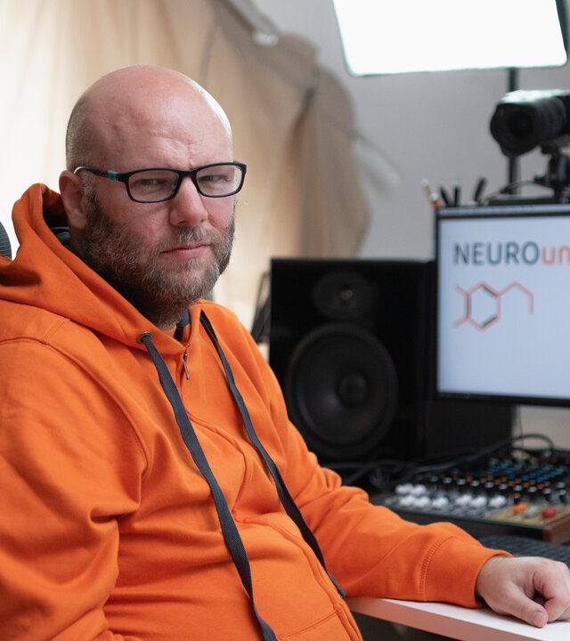 "einfach Mensch - Dave Remmel: Mein Gehirn tickt anders (2)": Dave Remmel sitzt am Schreibtisch und schaut in die Kamera.