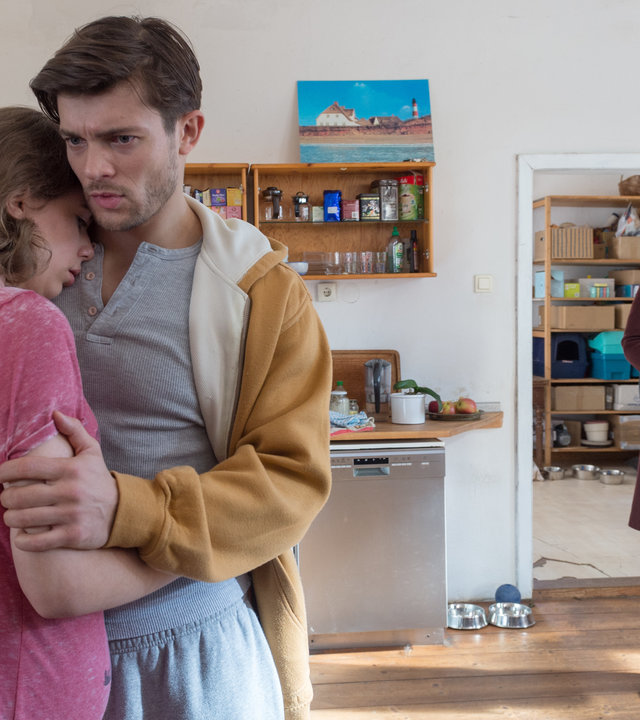 "SOKO Wismar – Taxi-Blues": Karoline Joost (Nike Fuhrmann) steht in der Wohnküche von Ella Preuss (Josepha Walter) und René Kwiatkowski (Eugen Bauder). Ella ist schwanger und wird von ihrem Freund tröstend in die Arme geschlossen.