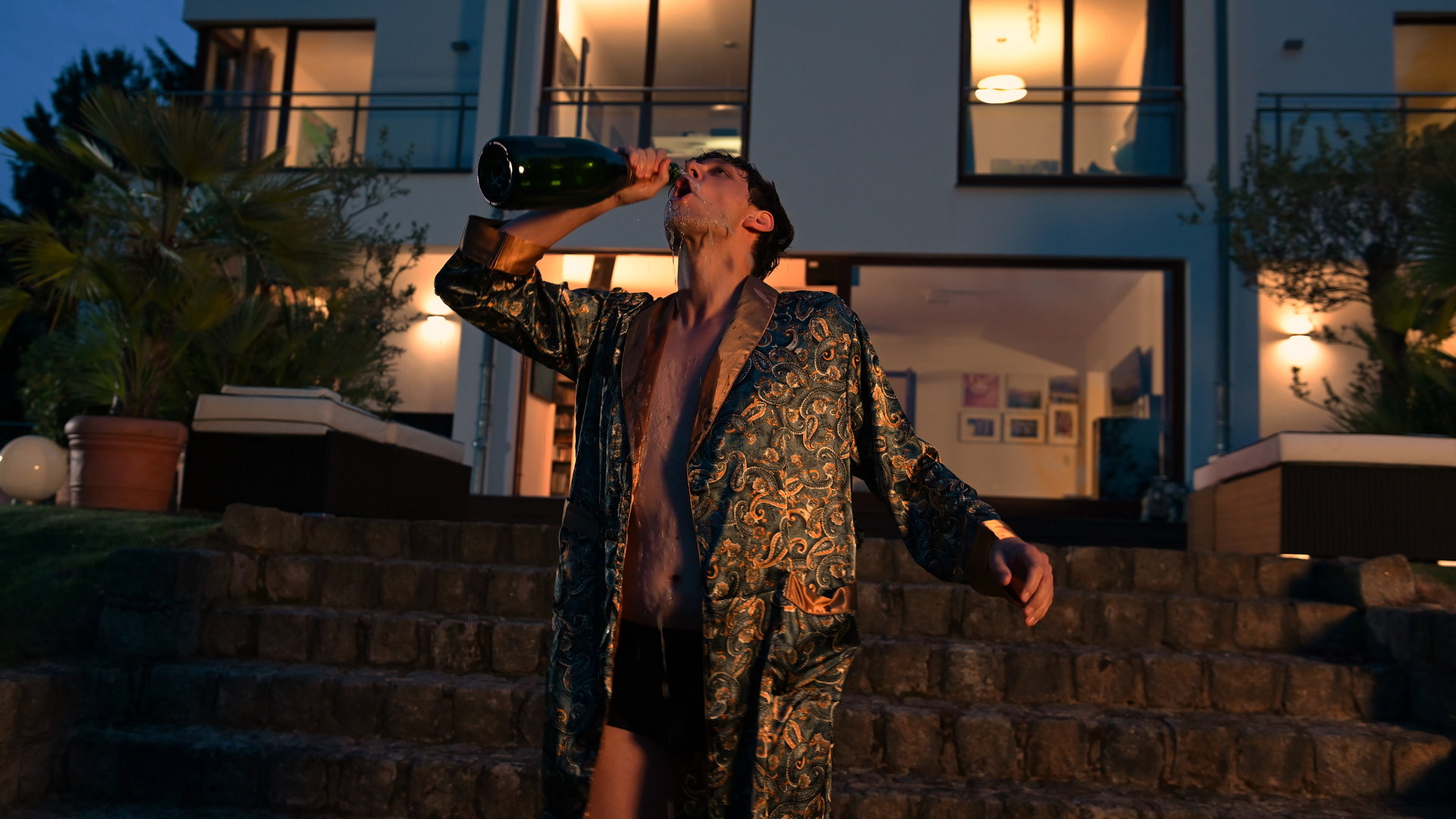 "SOKO Potsdam - Einmal Schlaatz, immer Schlaatz": Im Garten der Villa Roth steht Eiko Nehring (Franz Liebig) im Kimono und trinkt aus einer Champagnerflasche.