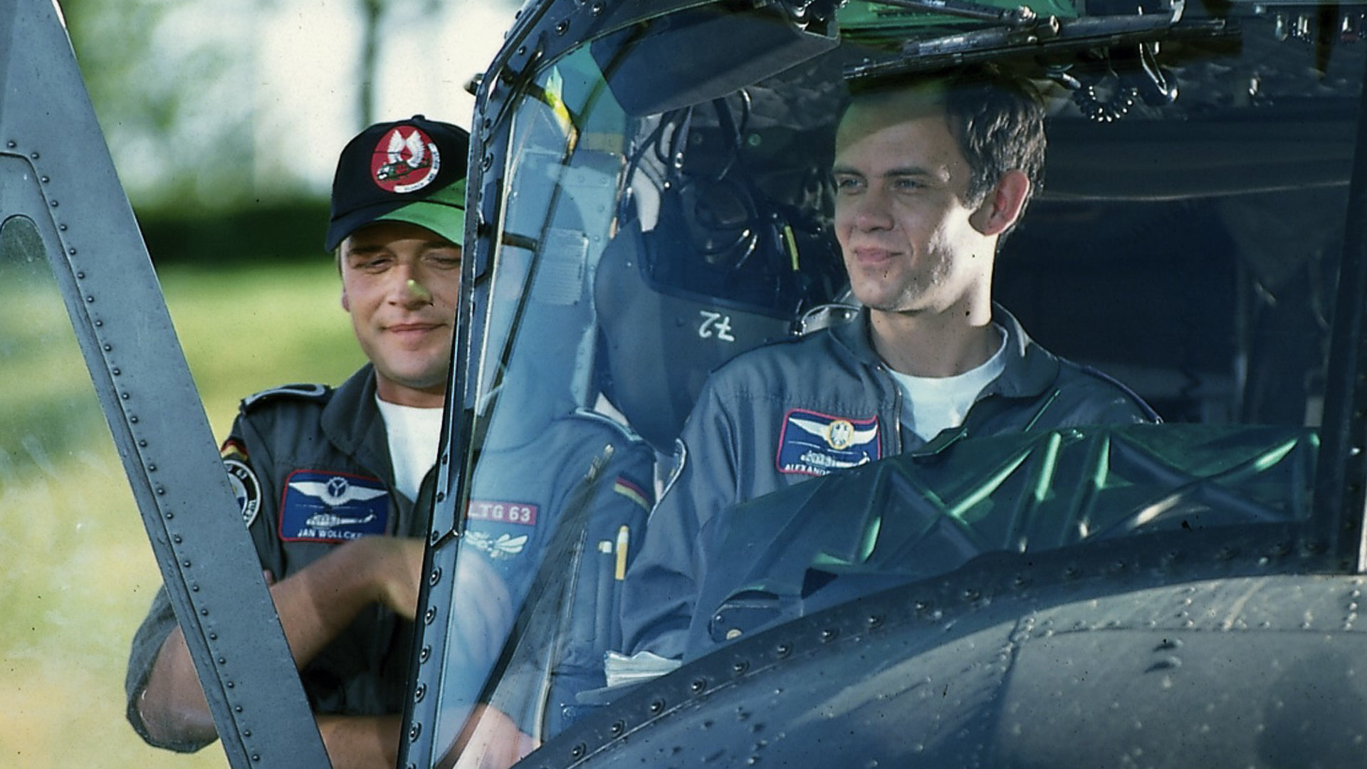 "Die Rettungsflieger - Kinderparadies": Pilot Alex (Matthias Leja) sitzt im Hubschrauber und Bordmechaniker Wollcke (Oliver Hörner) lehnt an der Seitentür.