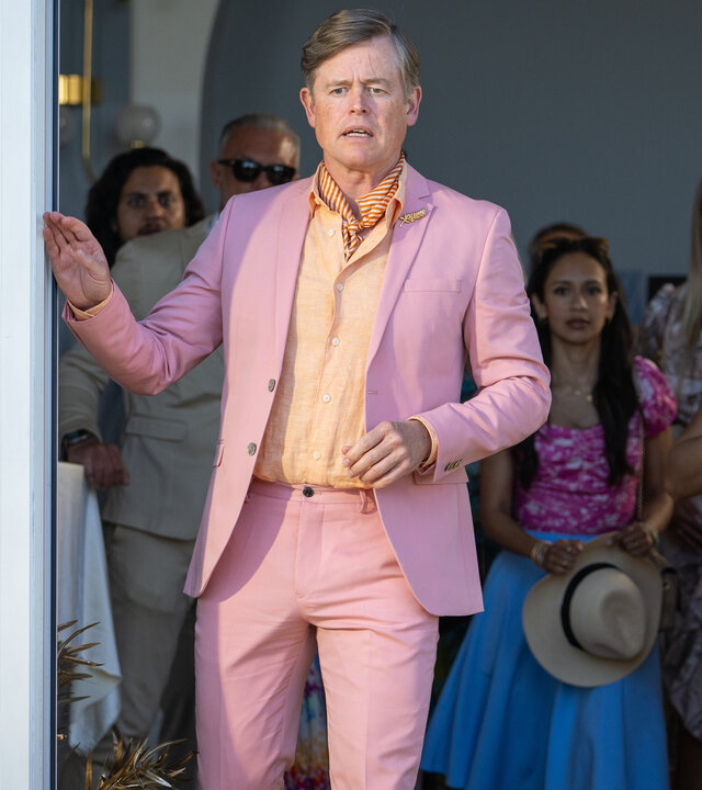 "Dan Sommerdahl - Tödliche Idylle: Miss Sunshine": Arne Lind (Caspar Phillipson) steht im Terrasseneingang eines Hotels und blickt entsetzt nach draußen. Seine rechte Hand greift zum offenen Schiebefenster. Er trägt einen Anzug in Rosa. Im Veranstaltungsraum hinter ihm blicken weitere festlich gekleidete Menschen (Komparsen) ebenso schockiert nach draußen.