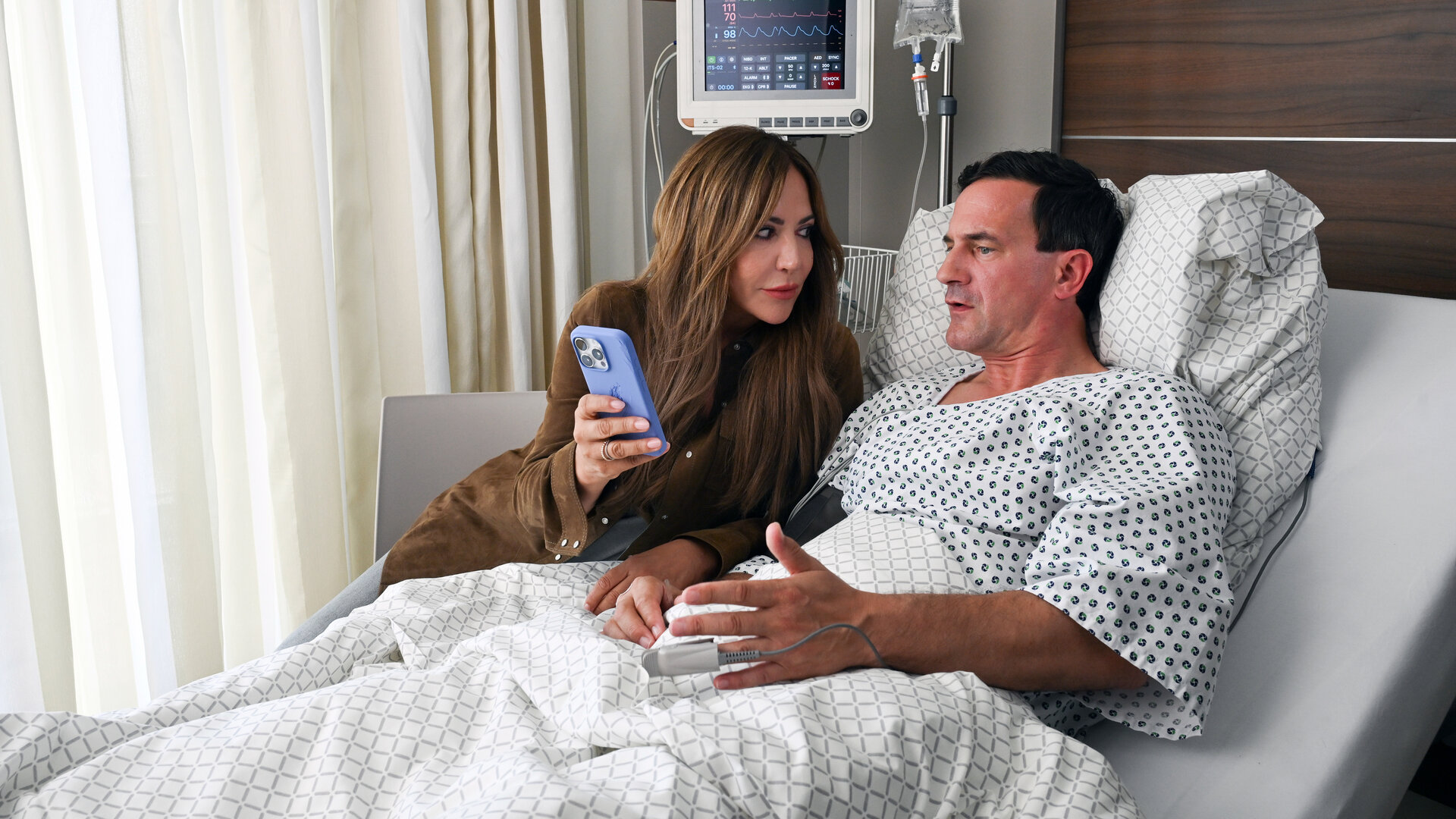 "Frühling - Vergiss mein nicht": Katja Baumann (Simone Thomalla) sitzt am Krankenhausbett von Friedel Gottwald (Sönke Möhring) und zeigt ihm etwas auf dem Handy, das sie in der Hand hält.