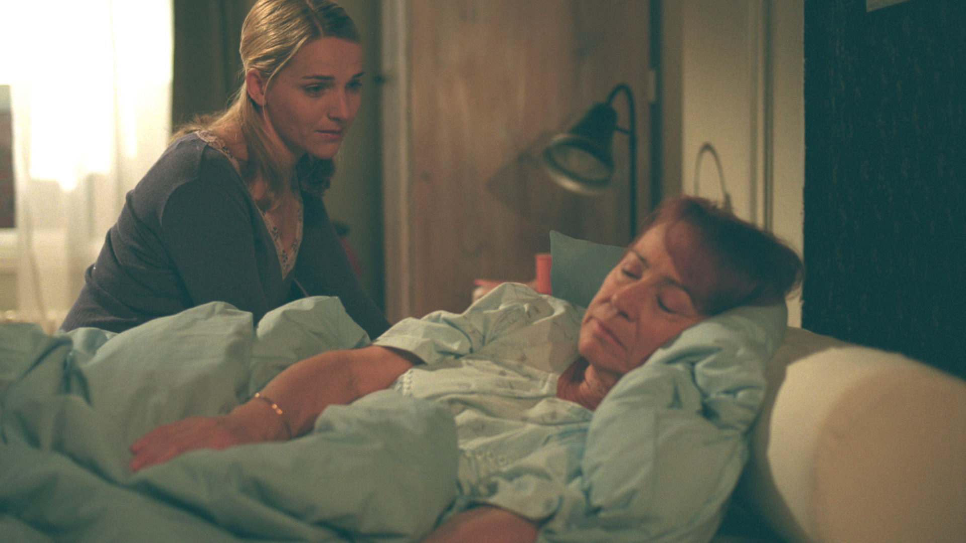 "Bianca - Wege zum Glück: Folge 50": Angst um ihre Oma: Während Oma Ursula (Annemone Haas) schläft, sitzt Bianca (Tanja Wedhorn) neben ihr am Bett und schaut sie liebevoll an.