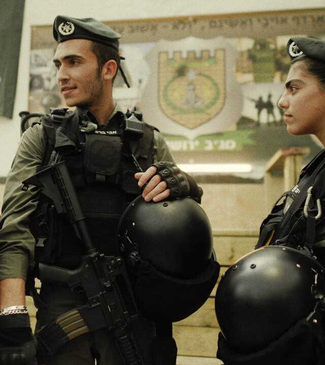 "Borders - Willkommen in Jerusalem": Kobi (Ido Elieli), Avi (Ben Sultan) und Miri (Noa Astanjelove) stehen in der Kaserne in voller Kampfausrüstung nebeneinander. Die Männer wirken gut gelaunt, Miri macht ein ernstes Gesicht.