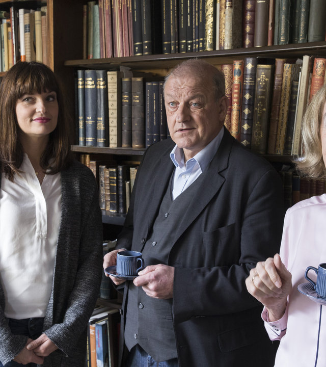 "Wilsberg - Der Betreuer": Ekki (Oliver Korittke), Alex (Ina Paule Klink), Wilsberg (Leonard Lansink) und Hanni Haffner (Gudrun Gundelach) stehen nebeneinander im Antiquariat. Wilsberg und Hanni Haffner halten Kaffeetassen in der Hand.