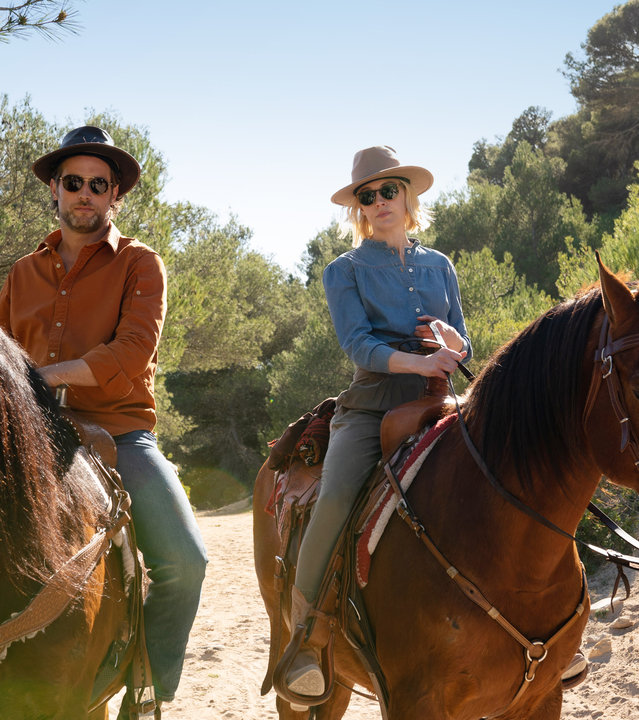 "The Mallorca Files - Der Gesetzlose": Max Winter (Julian Looman) und Miranda Blake (Elen Rhys) reiten im Sonnenschein nebeneinander auf braunen Pferden.
