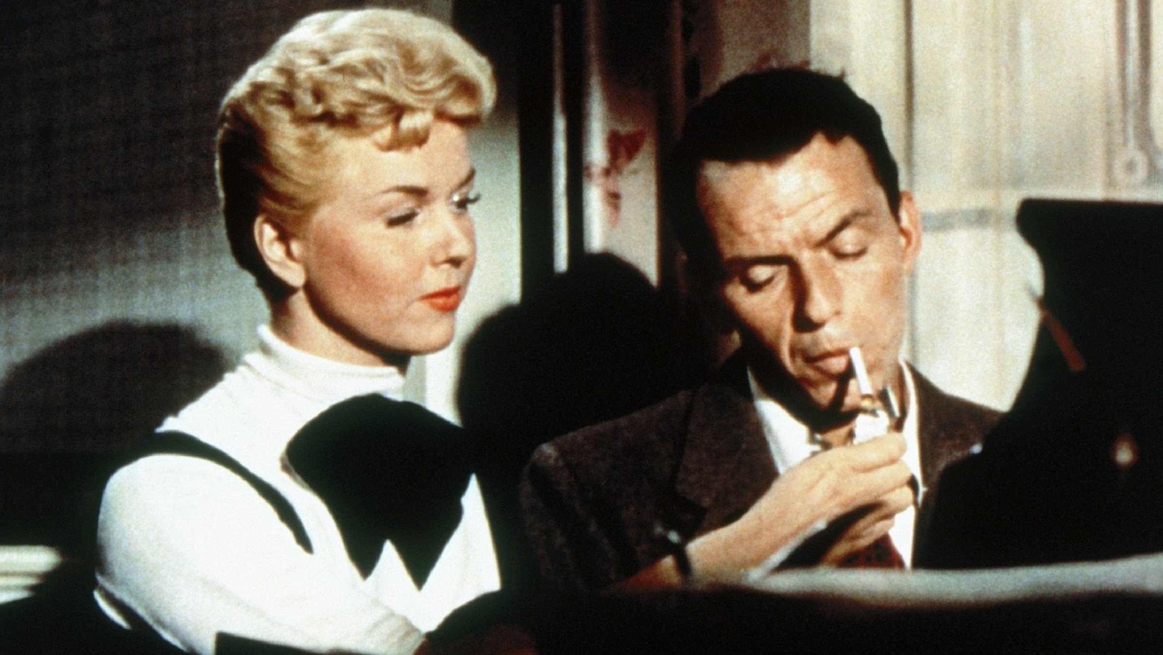 "Man soll nicht mit der Liebe spielen": Laurie Tuttle (Doris Day) sitzt neben Barney ‎Sloan (Frank Sinatra) ‎am Klavier. Er hat eine Zigarette im Mund, und Laurie gibt ihm Feuer.