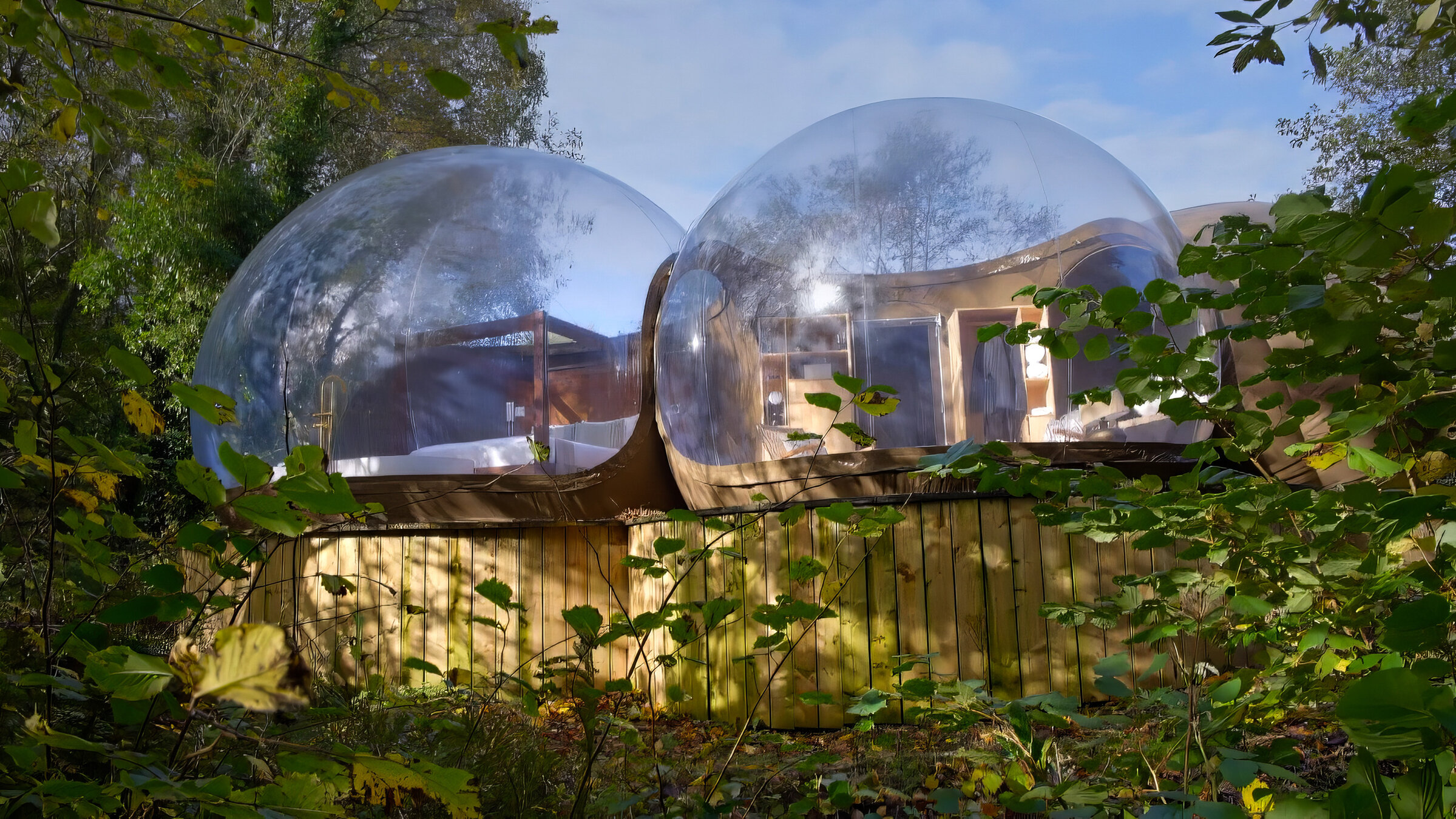"Die außergewöhnlichsten Hotels der Welt - Auszeit in der Natur": Zwei transparente Bubble-Hotels auf Holzplattformen, umgeben von Bäumen und grünem Laub.