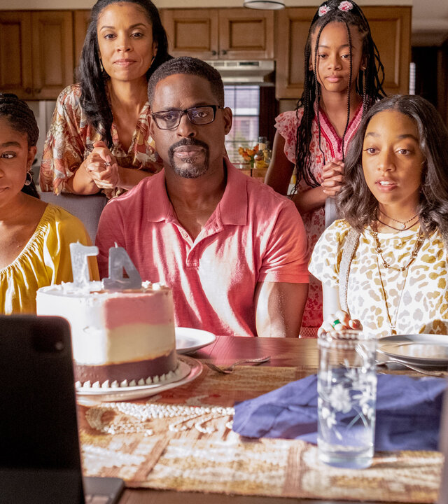 "This Is Us - Das ist Leben: Der Herausforderer": Randall (Sterling K. Brown) sitzt zwischen seinen Töchtern Déjà (Lyric Ross) und Tess (Eris Baker) an einem Esstisch. Vor ihnen steht eine Geburtstagstorte mit Kerzen sowie ein aufgestelltes Tablet. Hinter ihnen stehen Beth (Susan Kelechi Watson) und Annie (Faithe Herman). Alle blicken ernst nach vorn – bis auf Déjà, die grinsend zur Seite schaut.
