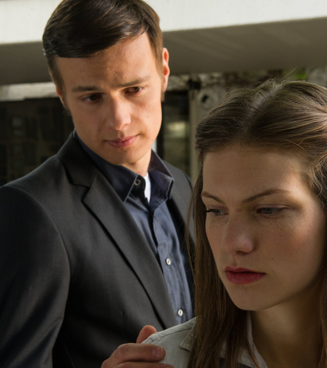 "SOKO Stuttgart - Der Priester ist tot": Cordula Seiffert (Anna Bullard) steht mit nachdenklichem Blick auf einem Hof. Claudius von Seggern (Leonard Hohm) steht hinter ihr und legt ihr die Hand auf die Schulter.