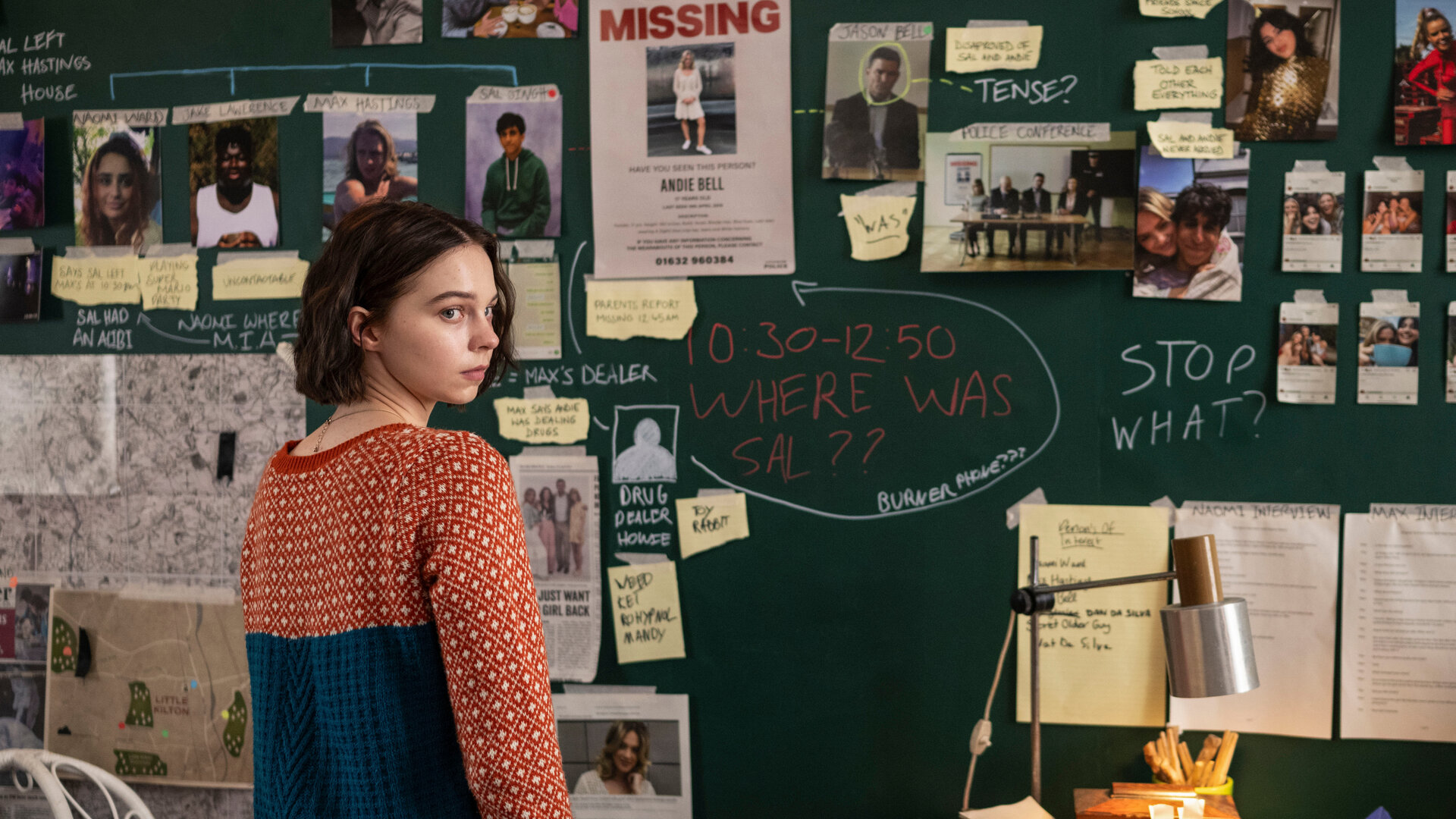 „A Good Girl's Guide to Murder – Codewort: Marshmallow“: Pip (Emma Myers) steht vor einer grünen Tafel, an der sie zahlreiche Dokumente und Fotos aus ihren Ermittlungen befestigt hat.