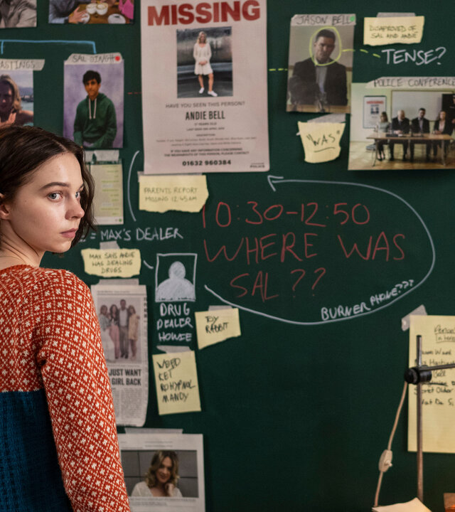 „A Good Girl's Guide to Murder – Codewort: Marshmallow“: Pip (Emma Myers) steht vor einer grünen Tafel, an der sie zahlreiche Dokumente und Fotos aus ihren Ermittlungen befestigt hat.