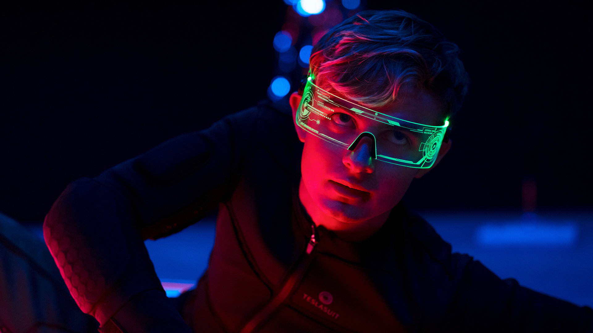"Alex Rider - Schlange": Alex (Otto Farrant) liegt auf dem Boden eines verdunkelten Raums. Dabei trägt er einen hautengen Motion-Capture-Anzug und eine grün leuchtende Brille.