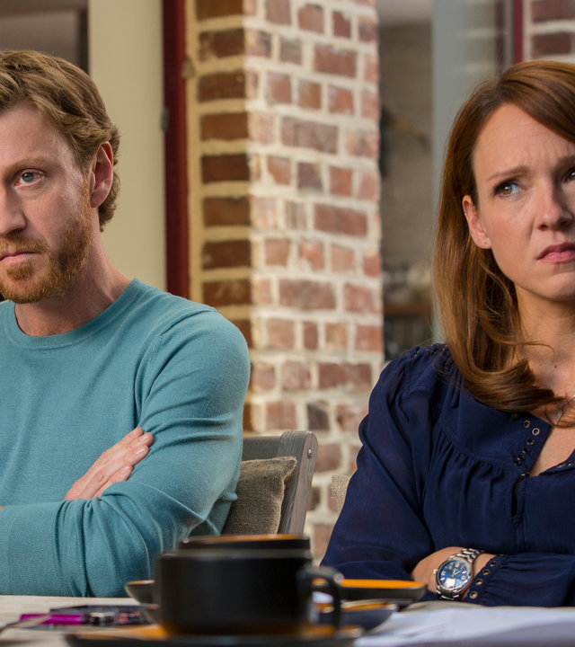 "Schatz, nimm du sie!": Toni (Carolin Kebekus) und Marc (Maxim Mehmet) sitzen mit verschränkten Armen nebeneinander an einem Tisch und schauen skeptisch nach vorne.