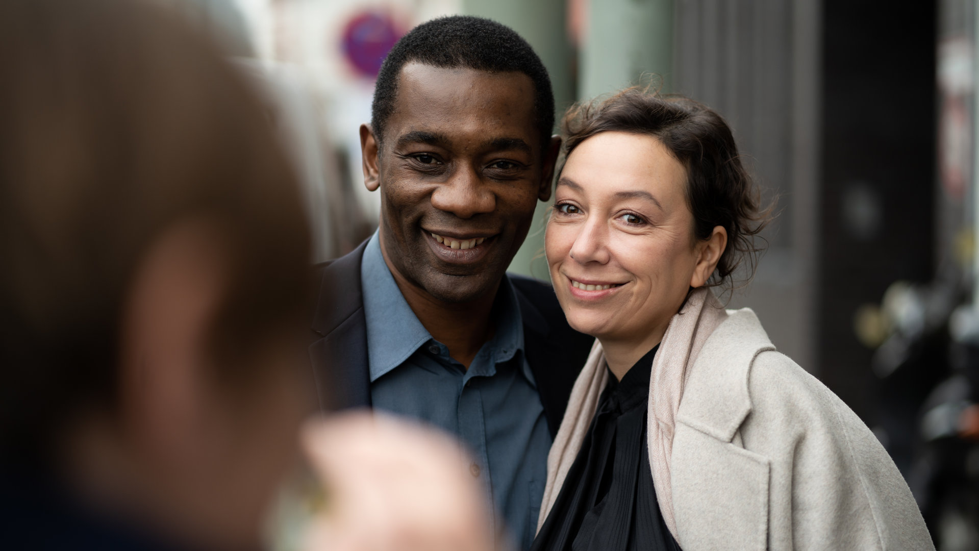 "Le Prince": Joseph (Passi Balende) und Monika (Ursula Strauss) stehen eng nebeneinander und lächeln in die Kamera, mit der jemand sie fotografiert.