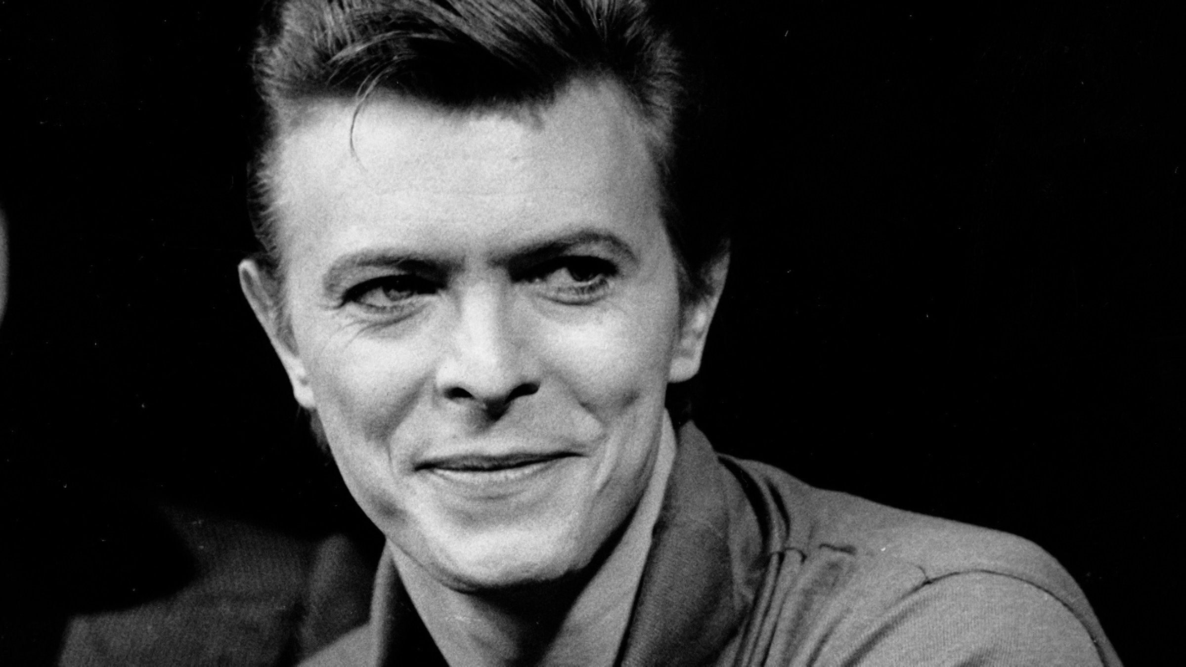 "The Day the Rock Star Died: David Bowie": Schwarz-Weiß-Portrait von David Bowie in einer Interview-Situation. Er blickt rechts an der Kamera vorbei.