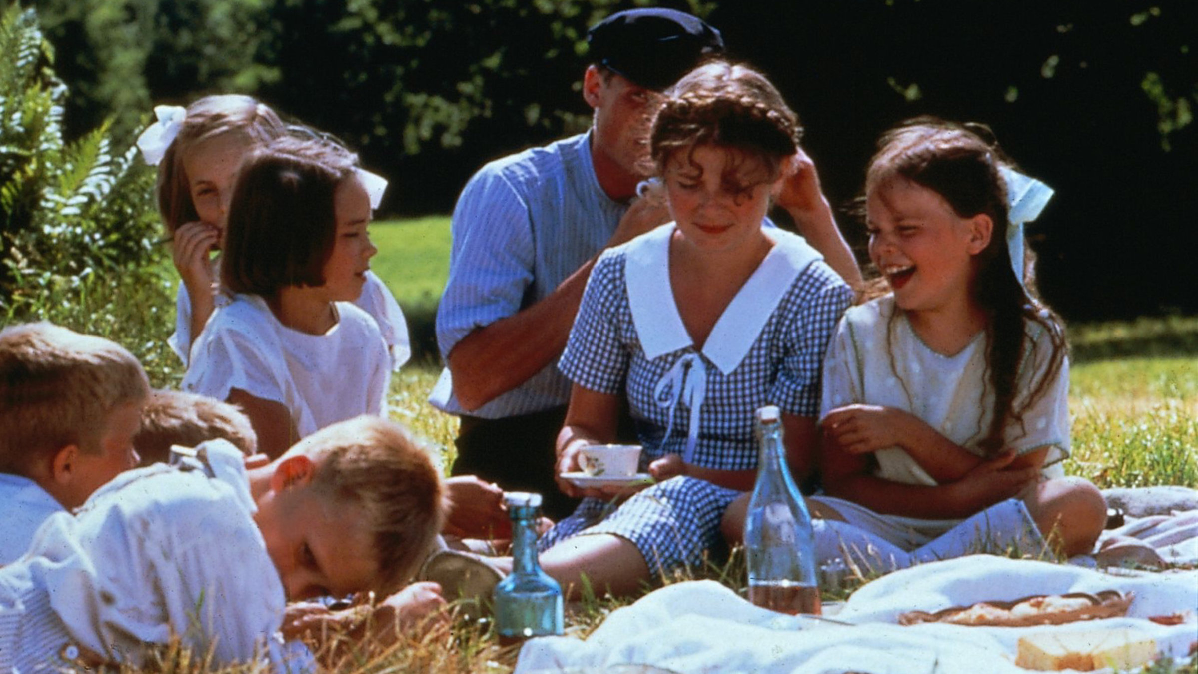 "Wir Kinder aus Bullerbü": Die Magd (Agda Louisa Raeder) sitzt mit den Kindern auf einer Picknickdecke im Grünen.