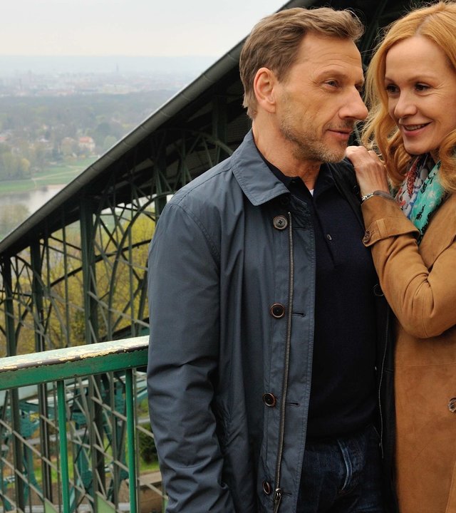 "Anne und der König von Dresden": Anne (Katja Flint) und Gregor (Richy Müller) stehen dicht nebeneinander vor der Standseilbahn von Dresden mit Blick aufs Elbtal.