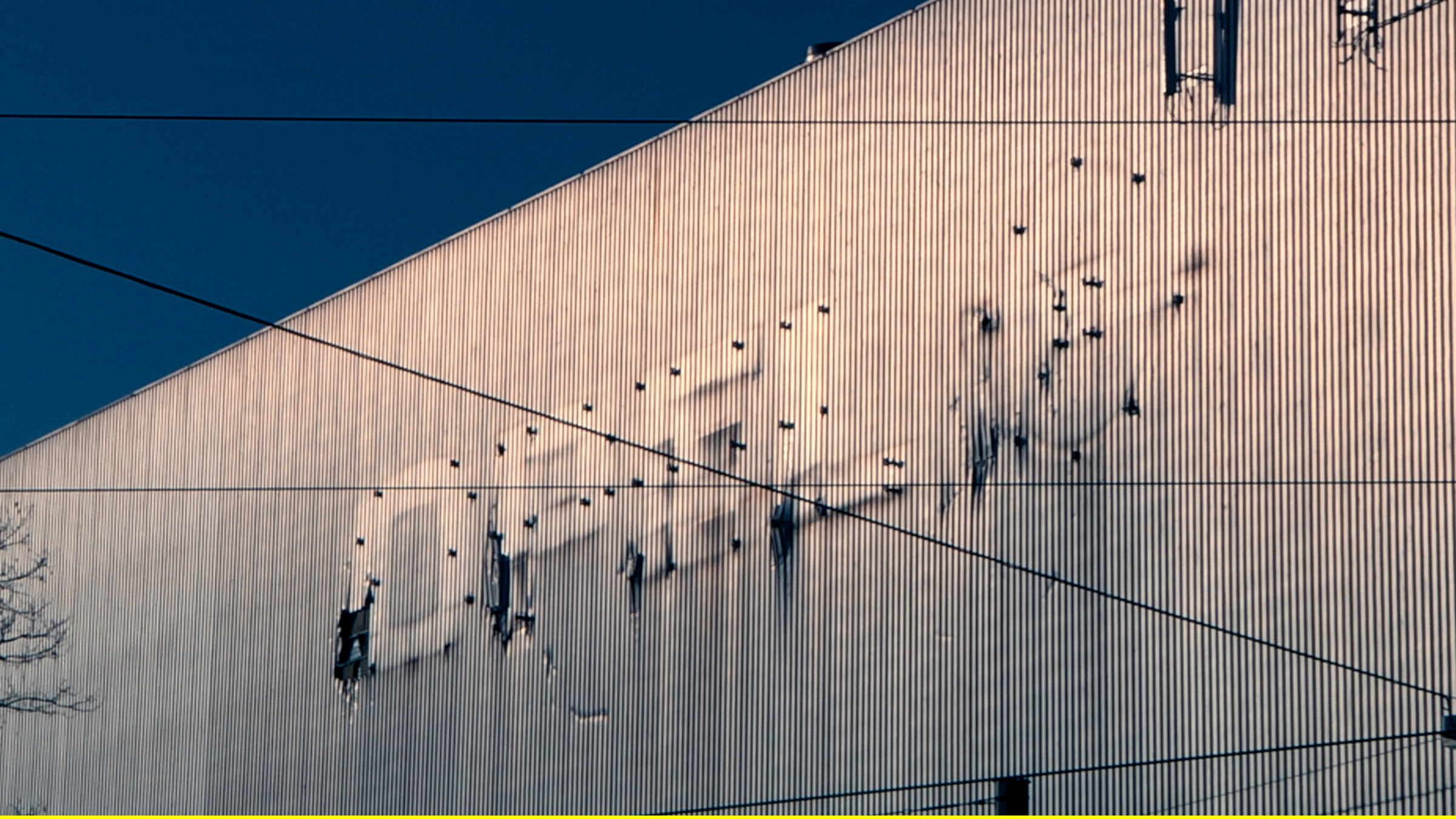 "We are all Detroit - Bochum, eine Stadt im Wandel": Fassade der ehemaligen Opel-Lackiererei in Bochum, Schatten des entfernten Unternehmenszeichens.