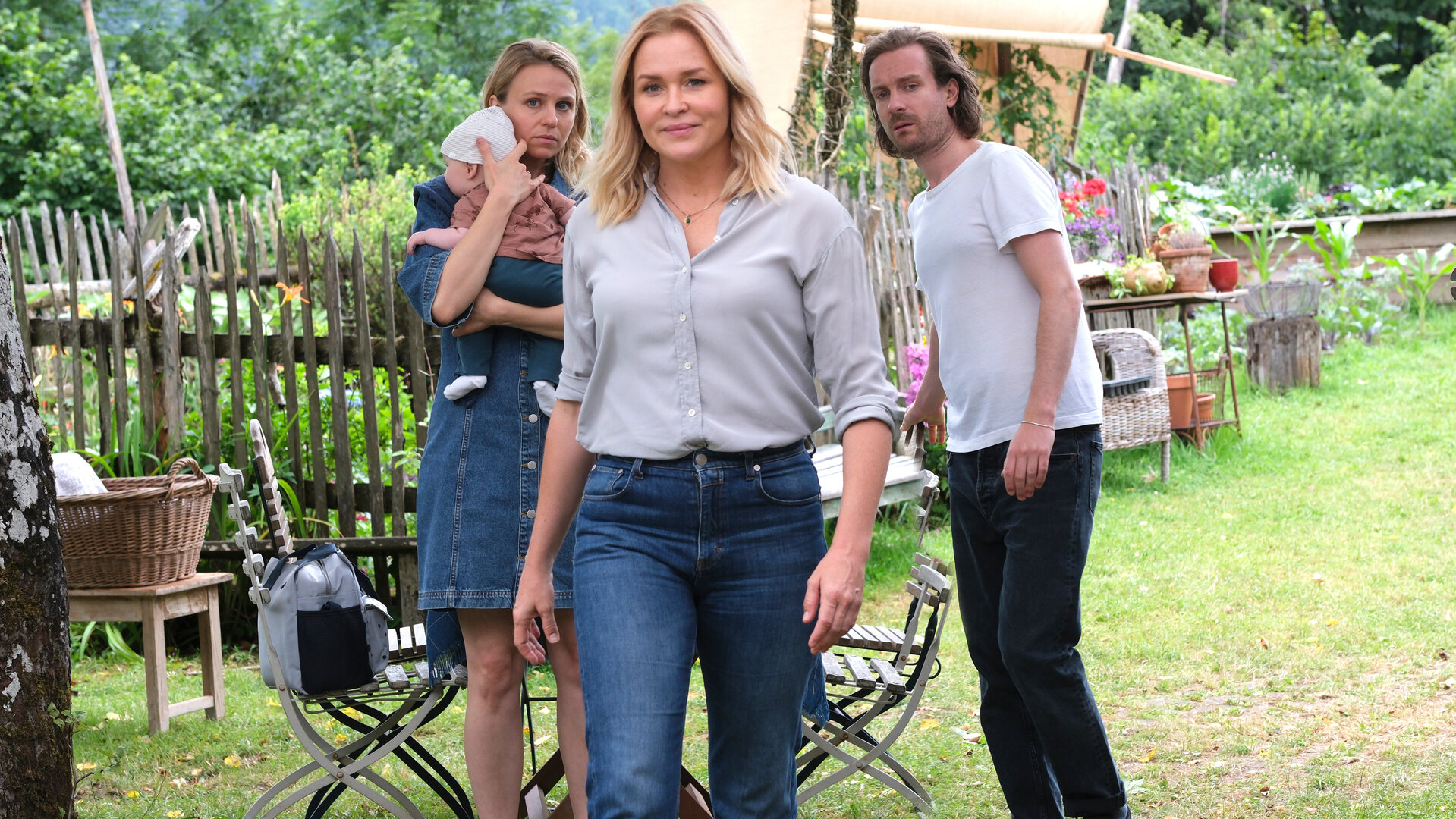 "Lena Lorenz - Vertauscht": Lena Lorenz (Judith Hoersch) kommt mit Annika (Teresa Rizos) und Raffael (Max Rothbart) Vollmer auf den Lorenzhof. Während Lena lächelt, schauen Raffael und Annika, die ein Baby auf dem Arm hält, sehr skeptisch drein.