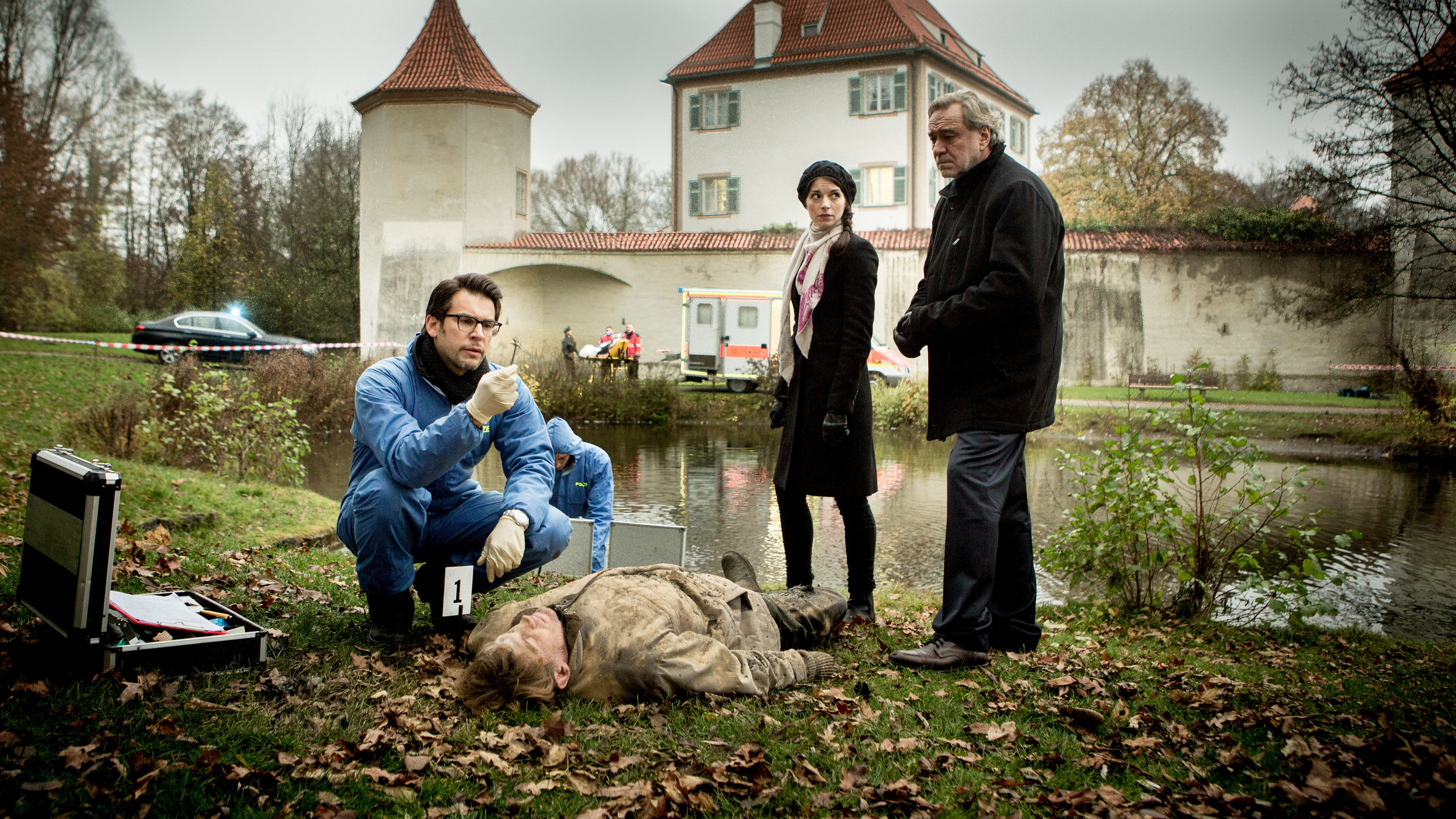 "SOKO 5113 - Sonnbach (1)": Dr. Weissenböck (Florian Odendahl) hockt neben einer Leiche und hält eine Pinzette mit Fell in der Hand. Katharina Hahn (Bianca Hein) und Arthur Bauer (Gerd Silberbauer) stehen neben der Leiche.