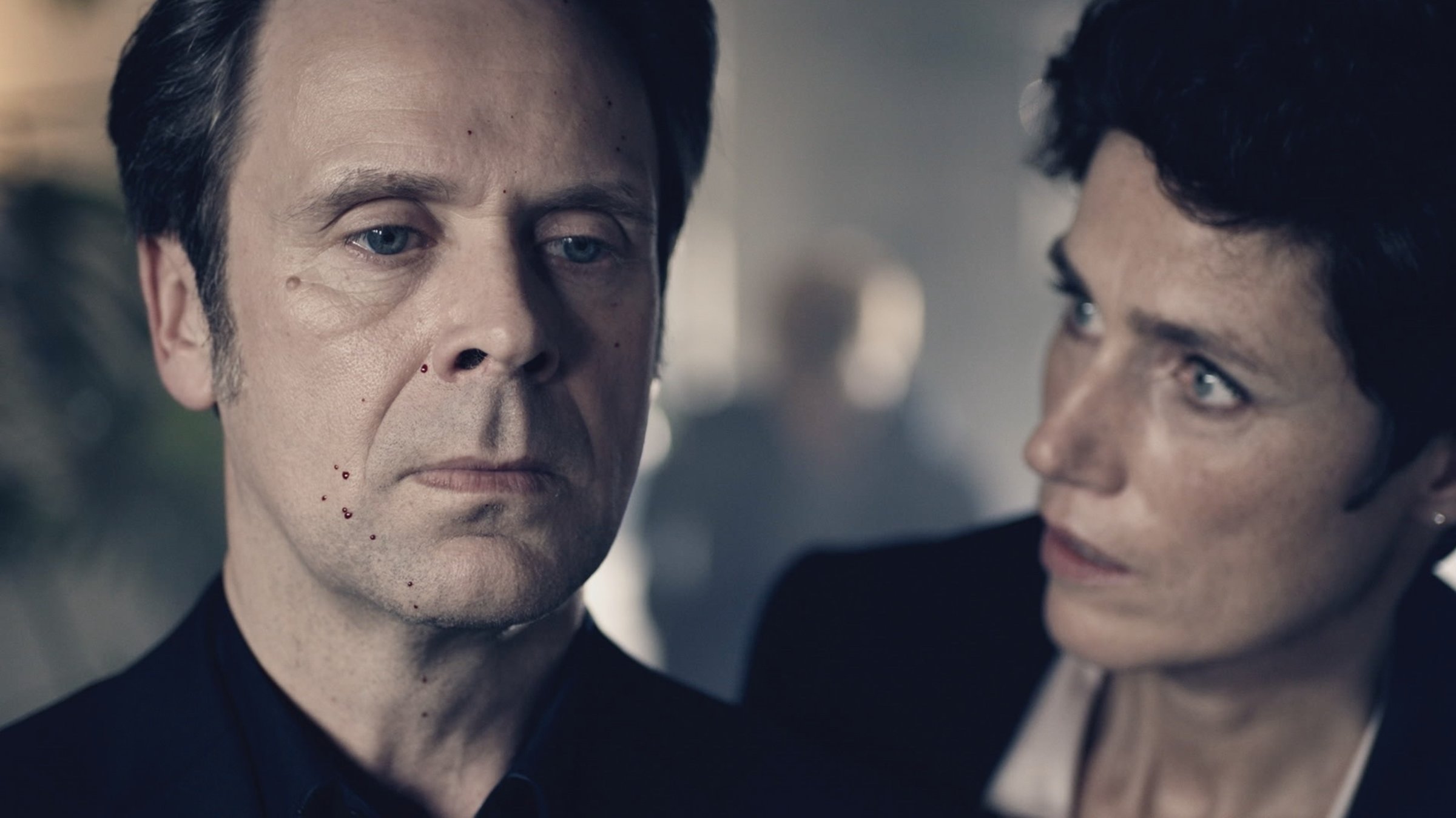 "Professor T. - Mord im Hotel": Professor T. (Matthias Matschke) steht betroffen im Raum, er hat Blutspritzer im Gesicht. Kriminaldirektorin Christina Fehrmann (Julia Bremermann) schaut ihn schockiert von der Seite an.