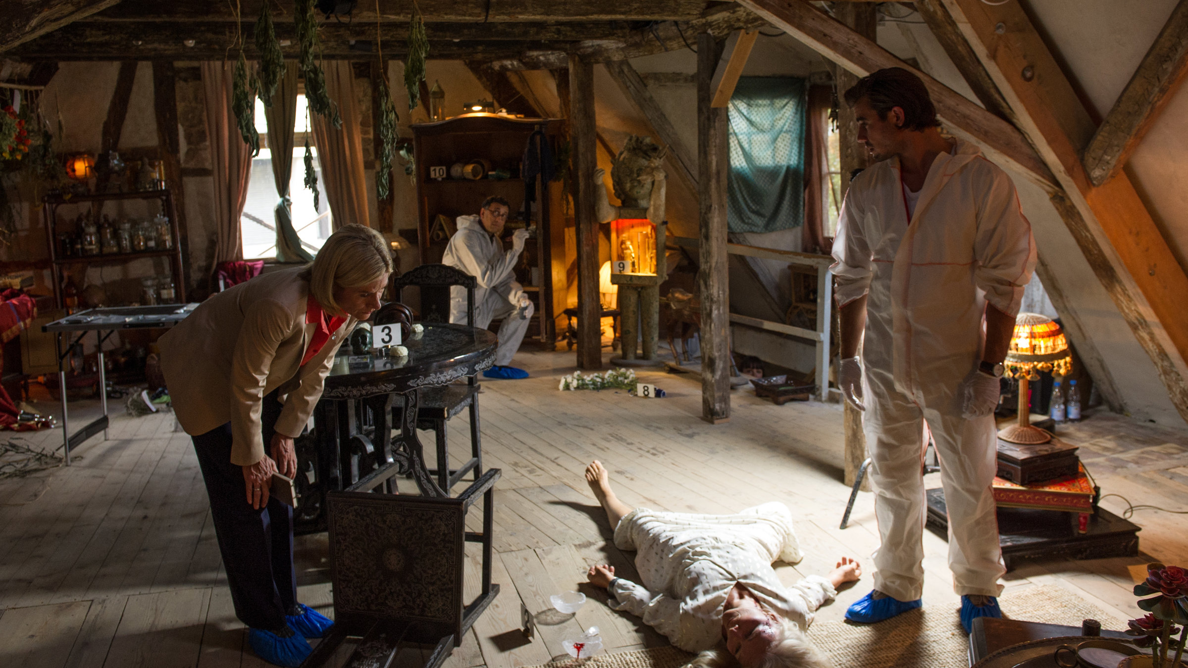 "SOKO Stuttgart - Das zweite Gesicht": Martina Seiffert (Astrid M. Fünderich) steht mit Benedikt Förster (Florian Wünsche) am Opfer Emma Brecht (Gesine Hannemann), die zwischen den beiden liegt. Jan Arnaud (Mike Zaka Sommerfeldt) sichert im Hintergrund Spuren an einem Schrank.