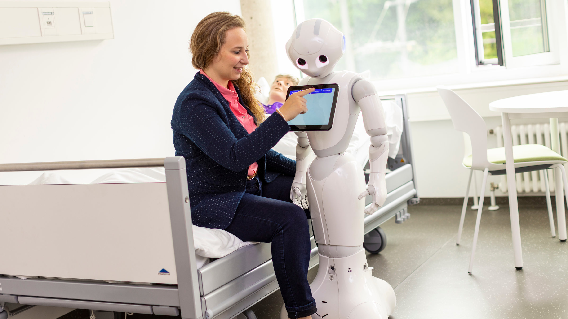 "37°: Schlauer als der Rest der Welt - Hochbegabte im Alltag": Pia mit dem Roboter Pepper, den sie im Rahmen ihrer Doktorarbeit entwickelt, in der Universität Ulm mit einem Patienten-Dummie im Hintergrund im Bett.